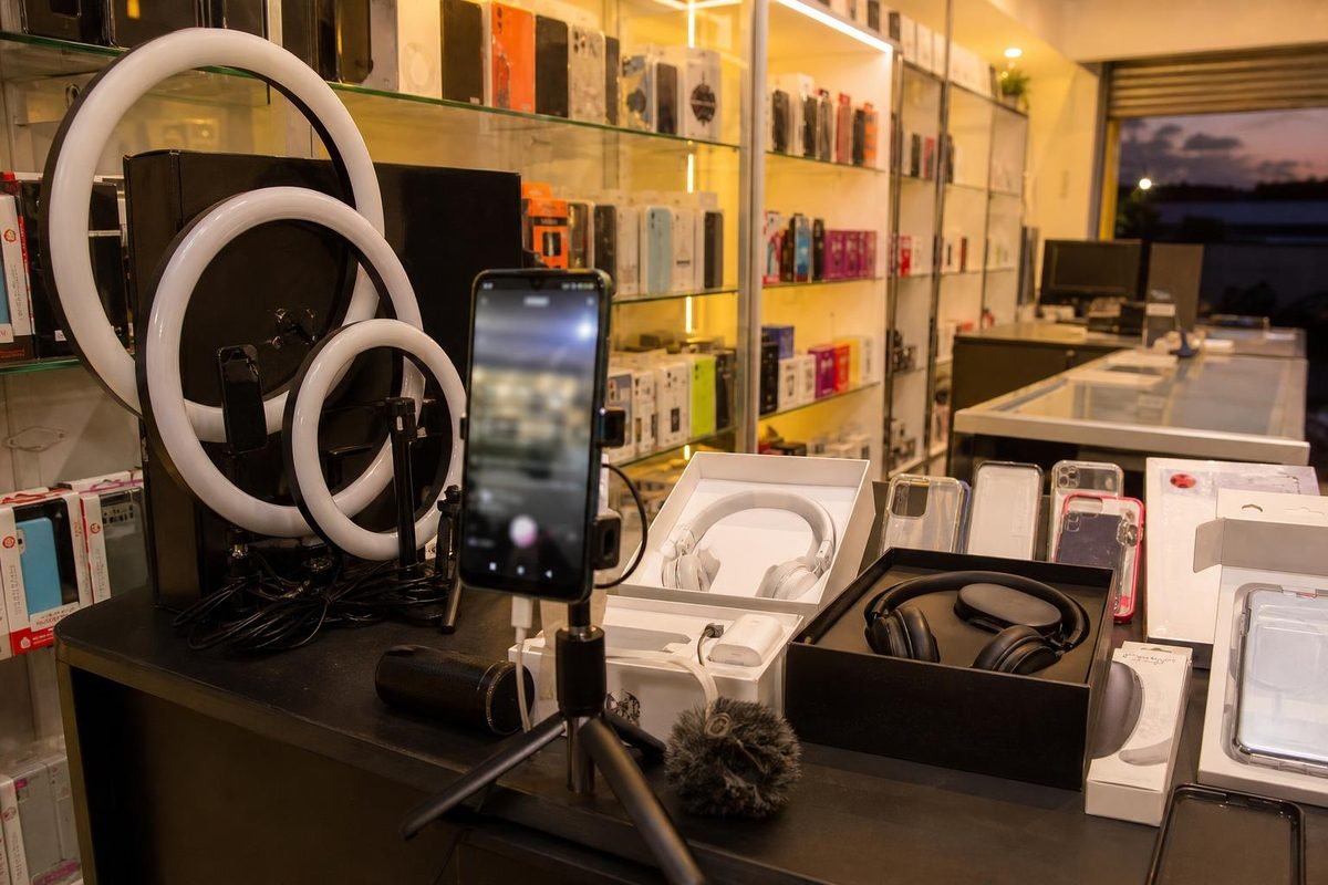 Loja de eletrônicos com celular gravando live e caixas de produtos