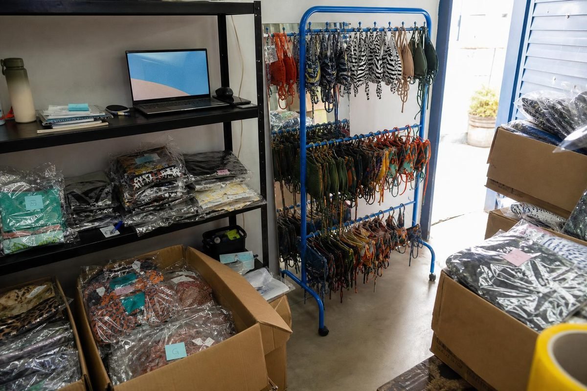 Retaguarda de loja com caixas, roupas embaladas e estoque pronto para subir